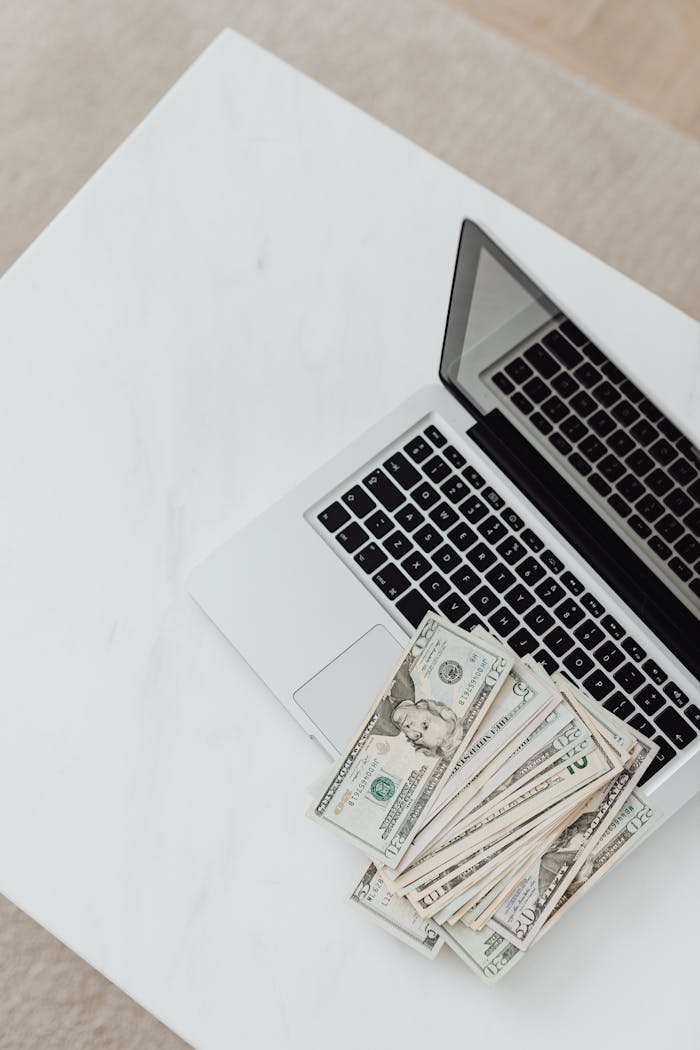 Overhead Shot of Dollar Bills on Top of a Laptop